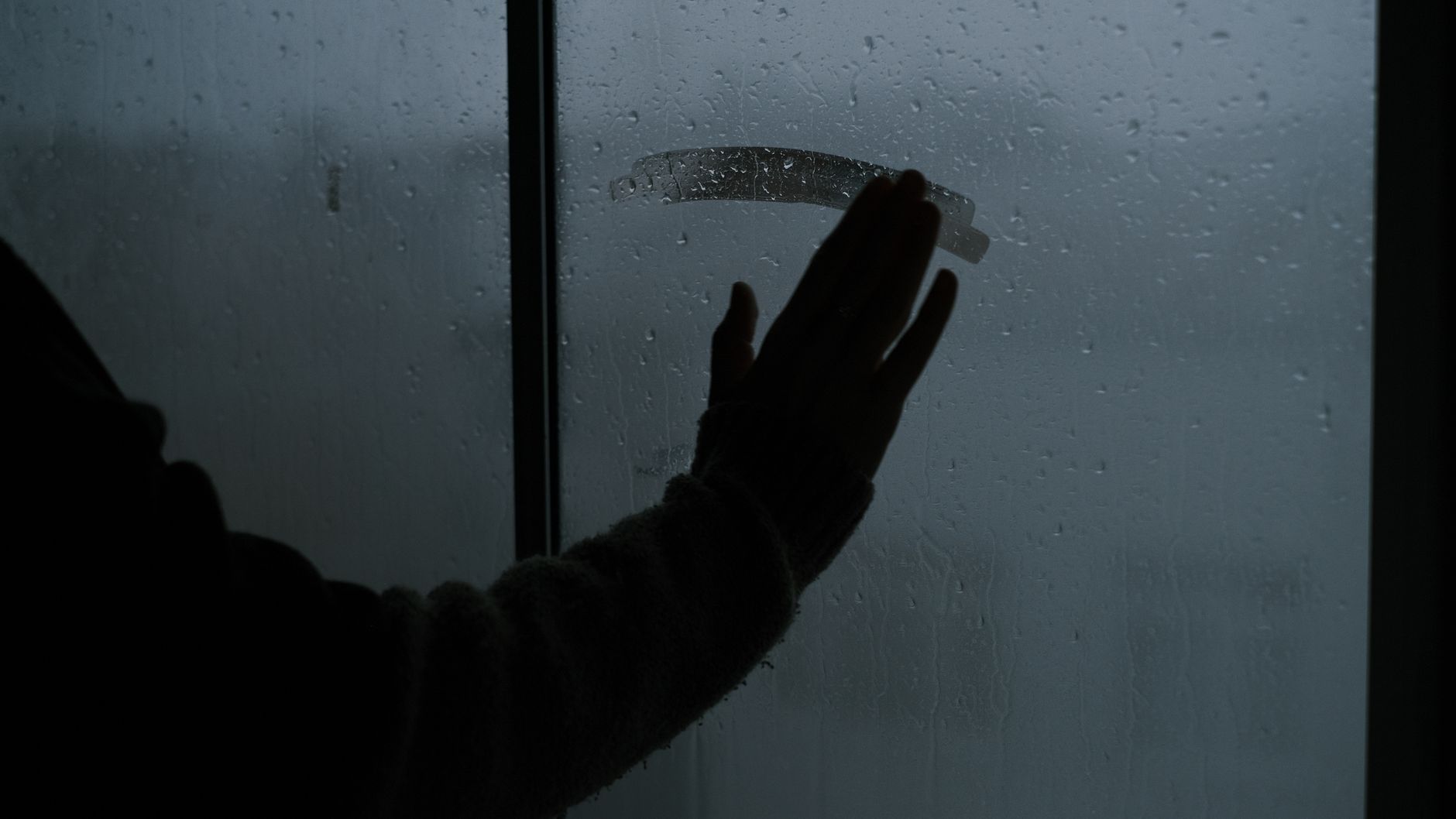 Main posée sur un mur froid révélant un pont thermique dans une maison